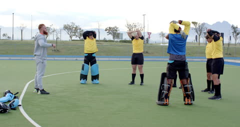 Hockey Team Stretching with Coach on Field for Pre-Game Warm-Up
