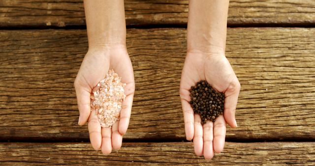 Hands Presenting Pink Salt and Black Peppercorns on Wooden Background - Download Free Stock Images Pikwizard.com