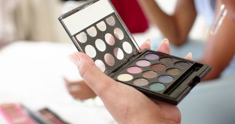 Female friends holding open eyeshadow palette showing colorful pans and neat nails