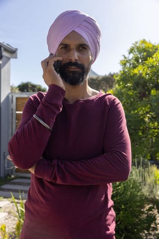 Indian Man Holding Smartphone Near Garden in Casual Attire
