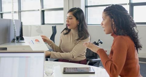Inclusive workplace meeting showing colleagues discussing charts with wheelchair nearby