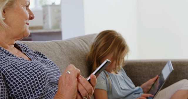 Grandmother and granddaughter using technology together on sofa - Download Free Stock Images Pikwizard.com