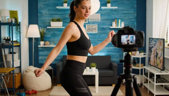 Recording home workout with dslr, female fitness creator filming living room routine