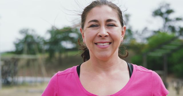Portrait of biracial woman wearing pink t-shirt looking at camera and smiling. Female fitness, challenge and healthy lifestyle.