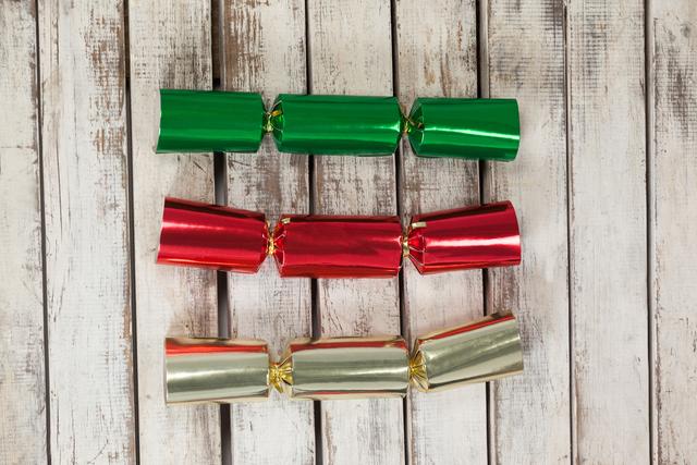 Red, green and golden Christmas crackers on wooden table