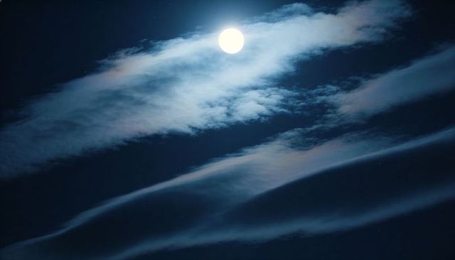 Full Moon Casting Halo Over Wispy Clouds and Starry Night Sky