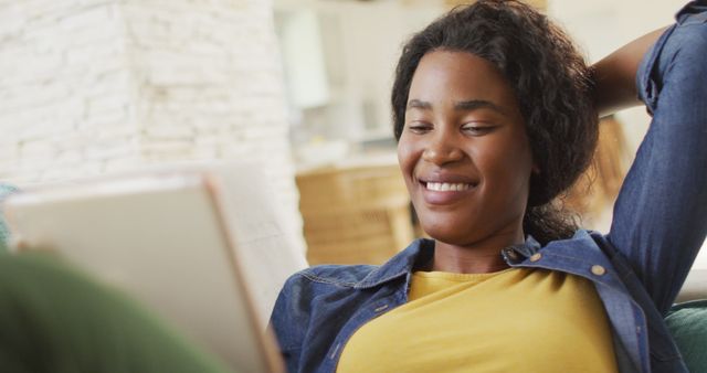 Woman smiling while using tablet, indoors, relaxation, enjoying leisure time. Useful for promoting home technology, lifestyle blogs, online education, casual living scenarios.