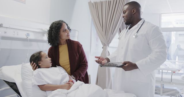 Doctor having serious consultation with concerned mother by bed of hospitalized child. Professionally dressed healthcare provider holding a tablet, discussing medical care plans. Perfect for healthcare, medical consultation content, patient care initiatives, family healthcare services promotions.