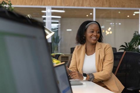 Smiling professional woman leading team discussion in modern open-plan office workspace