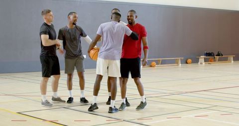 Five men greeting after pickup game in basketball huddle on indoor gym court