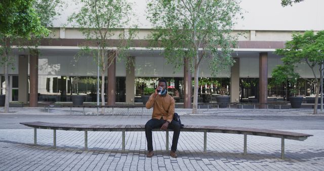 Man sitting on bench and drinking coffee in modern urban plaza - Download Free Stock Images Pikwizard.com