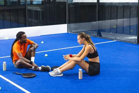 Diverse partners resting on indoor padel court after training