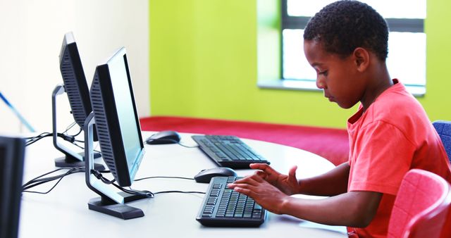 Young boy intensely focussed during computer work in a modern classroom. Can be used for educational materials, school brochures, technology and learning websites, or articles discussing digital literacy in schools.