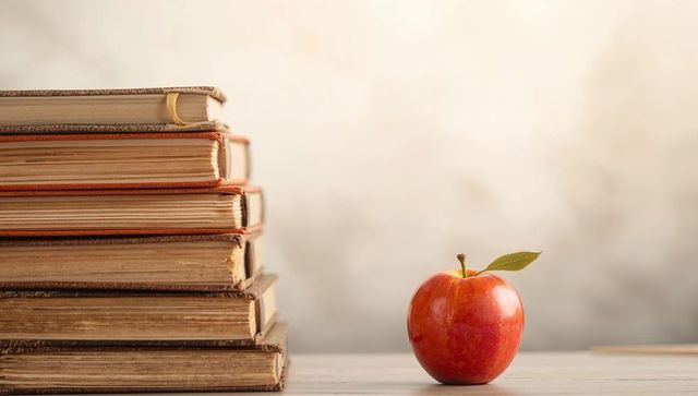 Stack of Vintage Books with Red Apple on Table