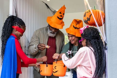 African american family celebrating halloween while handing out candy at doorway
