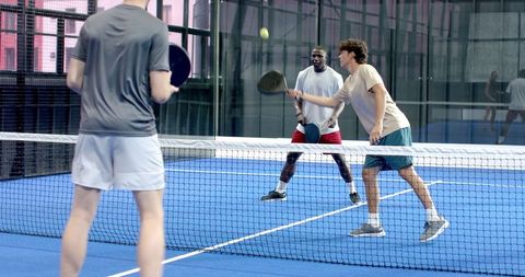 Diverse friends playing padel tennis on blue court