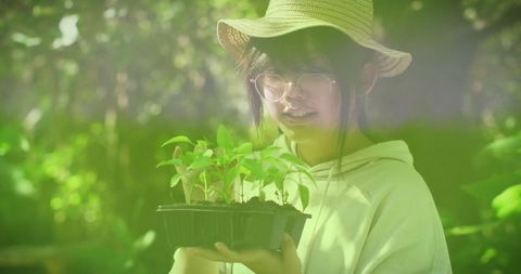 Young Asian Girl Holding Plant in Forest