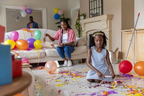 African american family cleaning up colorful birthday party in bright living room