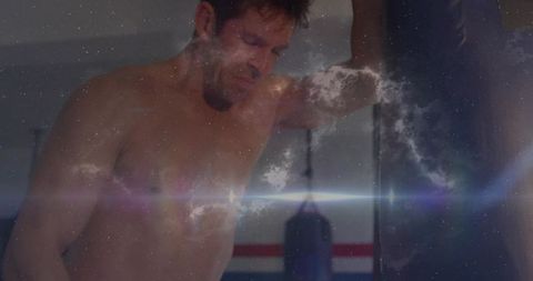 Shirtless boxer resting against heavy bag with nebula double exposure and lens flare