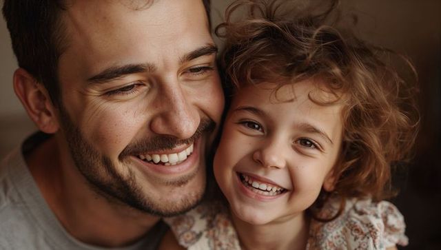 Smiling father and daughter pressing cheeks together sharing joyful closeup family bond