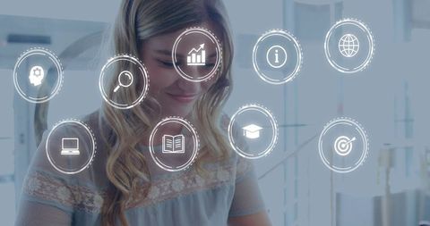 Young woman studying at desk with translucent digital education icons overlay focused study