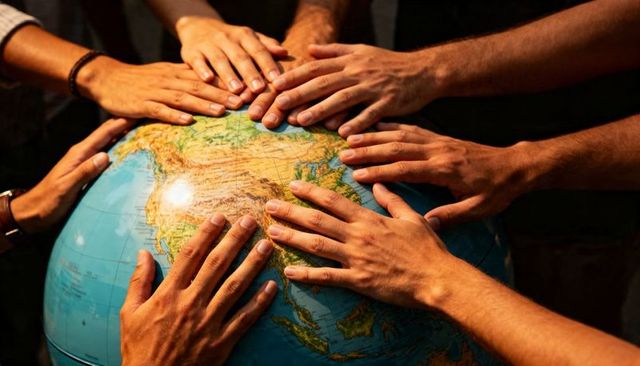 Hands pressing on globe representing global teamwork and shared responsibility