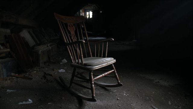 Lonely Wooden Rocking Chair in Dark Abandoned Attic