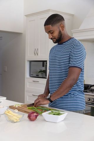 Man slicing green onions in modern kitchen for healthy meal prep