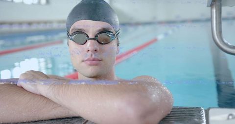 Swimmer resting at pool edge with goggles and swim cap