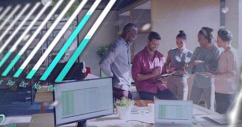 Creative team collaborating with tablets and laptops around shared desk in bright open-plan office