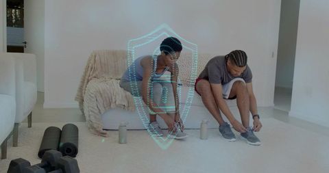 Couple tying running shoes at home before workout with yoga mats dumbbells for wellness