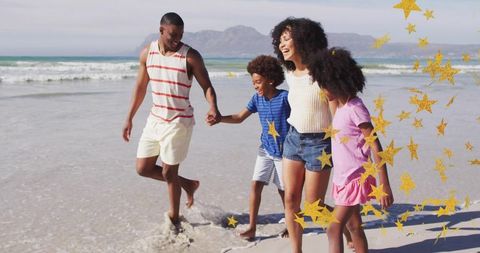 Joyful family walking on sunlit beach holding hands laughing with gold star confetti