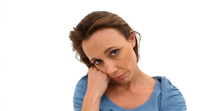 This image shows a woman wearing a blue shirt with a thoughtful and pensive expression, resting her head on her hand. It is ideal for topics related to emotional health, contemplation, solitude, or personal reflection. The white background makes it versatile for use in articles, blogs about mental health, psychology, or lifestyle content.