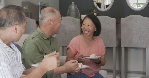 Asian Seniors Enjoying Cake and Laughter at Home Celebration