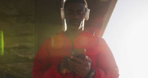 Man Enjoying Music on Smartphone with Headphones Outdoors, Ambient Sunlight - Download Free Stock Images Pikwizard.com