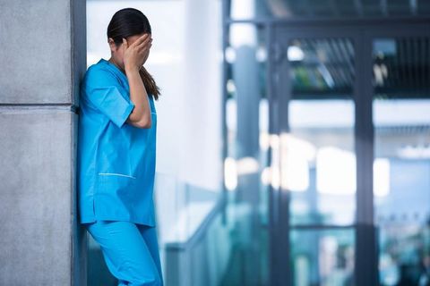 Stressed Nurse Standing Alone in Hospital Corridor - Download Free Stock Images Pikwizard.com