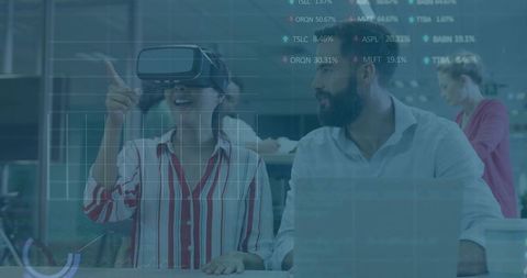 Woman wearing vr headset pointing at data overlays during office collaboration