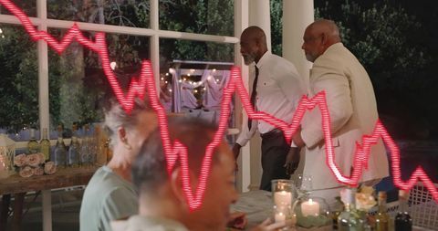 Businessmen reacting to market downturn during outdoor dinner with candles and wine