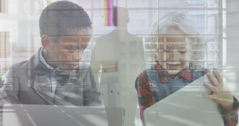 Children collaborating using laptop and tablet in modern classroom with city reflections