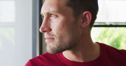 Reflective Man Gazing Through Window at Home