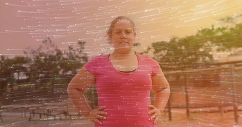 Confident woman in pink sports attire surrounded by dynamic light trails