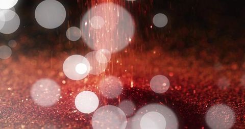 Shimmering red glitter surface glowing with falling sparks and soft bokeh highlights