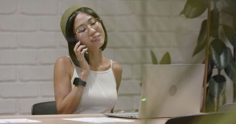 Asian woman engaged in dynamic office meeting while multitasking