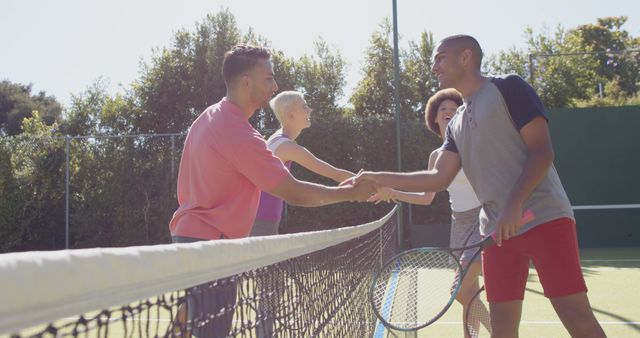 Mixed gender players in casual tennis attire shaking hands at net after friendly doubles match on outdoor court. This can be used for promoting fitness, sportsmanship, community activities, and recreational sportsmanship.