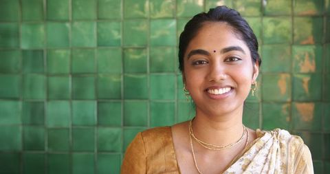 Indian woman in traditional sari smiling against green background