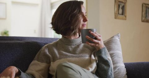 Woman Relaxing on Cozy Sofa with Coffee Cup