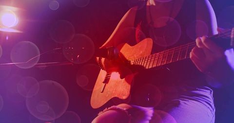 Teen Strumming Acoustic Guitar on Dim Stage with Microphone, Red Purple Spotlight Bokeh
