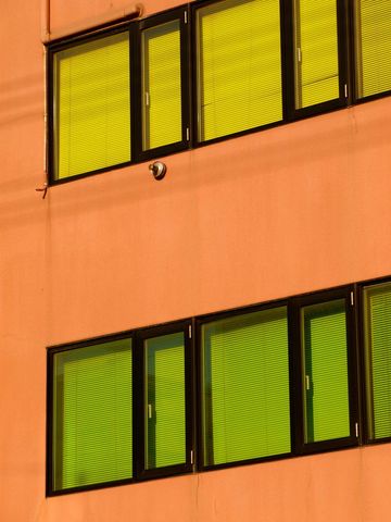 Coral Facade Featuring Neon Green Blinds, Black Window Frames and Security Camera