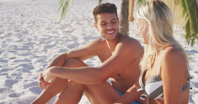 Happy diverse couple smiling and talking on beach. Lifestyle, realxation, nature, free time and vacation.