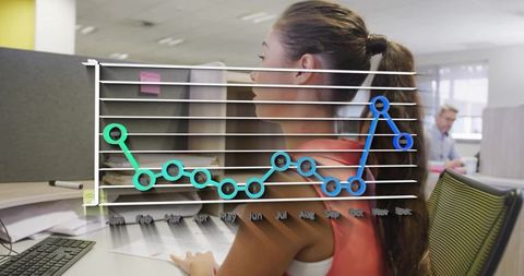 Businesswoman reviewing documents at open-plan desk with line chart overlay showing monthly trends